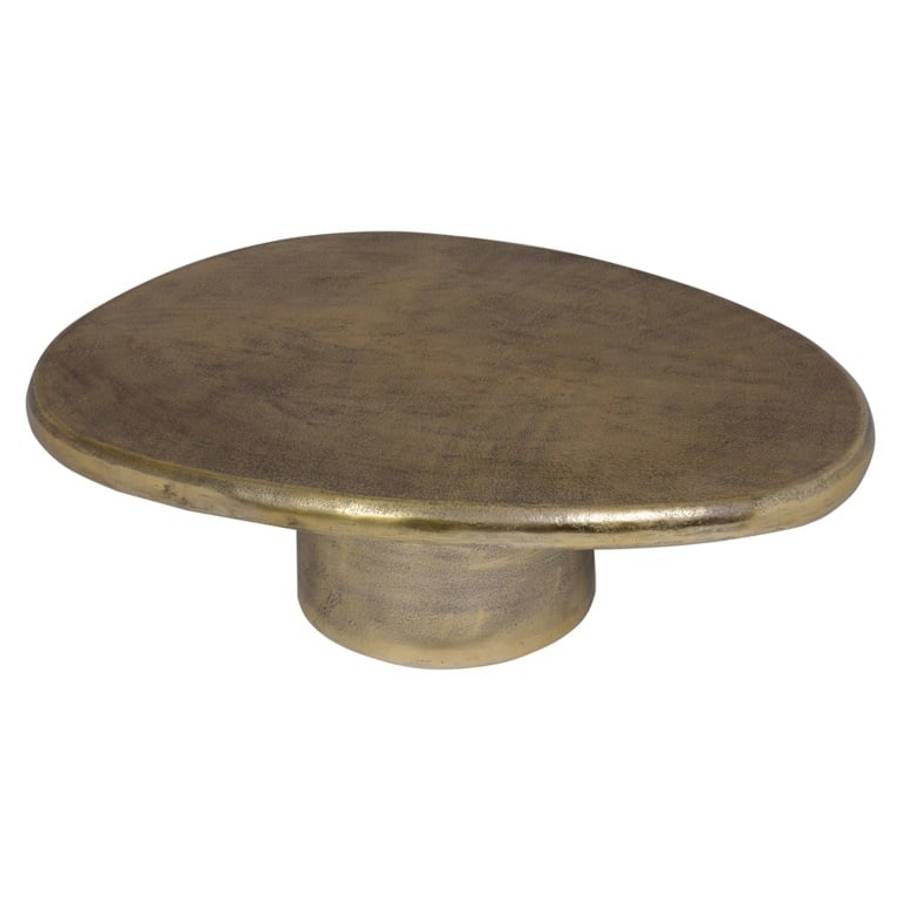 Ein Couchtisch namens „Pulitzer” in gebürstetem Gold. Der Tisch hat eine ovale Tischplatte mit glatter, polierter Oberfläche und einem zylindrischen Sockel.