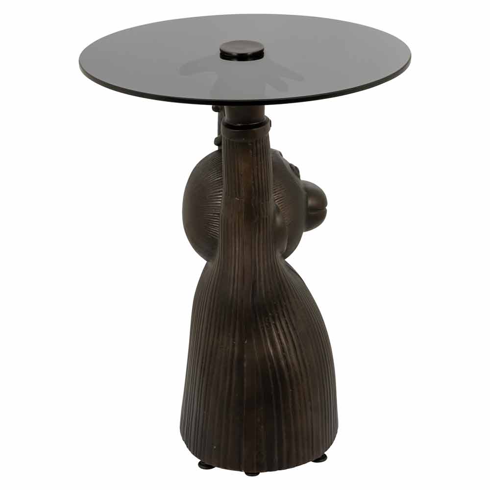 Eleganter Beistelltisch mit stilisierter Figur als Basis, die die runde Tischplatte trägt. Dunkle Töne, modernes Design.