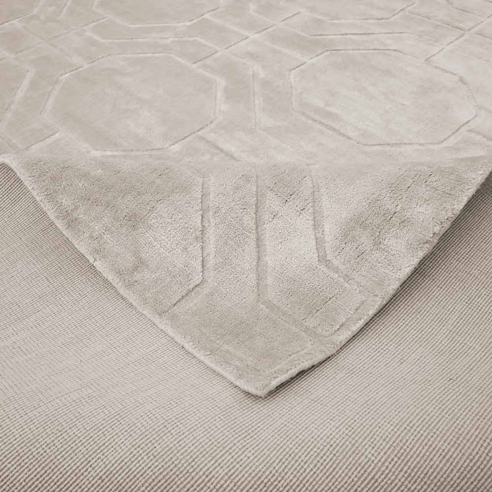 Detailansicht eines hellen Teppichs mit dezentem geometrischen Muster und verschiedenen Schattierungen, die das Muster bilden. Ideal für moderne Wohn- oder Büroräume.