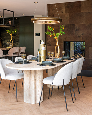 Moderner Speisebereich mit rundem Holztisch, sechs Stühlen, einem eleganten Lichtobjekt darüber und einem gedeckten Tisch, der auf ein Essen vorbereitet ist
