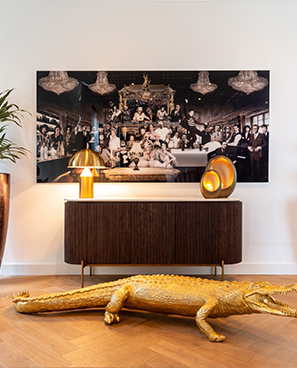 Modernes Wohnzimmer mit einem Bild, farbigen Lampen und einer goldenen Alligator-Skulptur.
