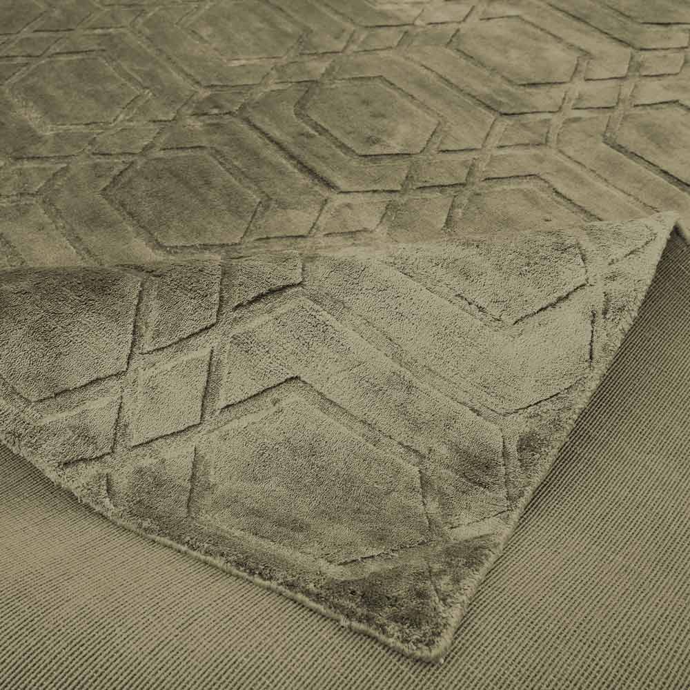Teppich Liva 200x300 (olive) Nahaufnahme eines Teppichs mit einem strukturierten Muster, das Kopfsteinpflaster ähnelt. Der Teppich ist über sich selbst gefaltet, wodurch die Dicke und die Unterseite sichtbar sind.